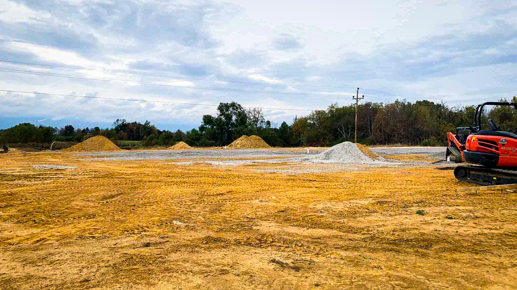 red dirt with gravel and dirt piles and Kubota bobcat